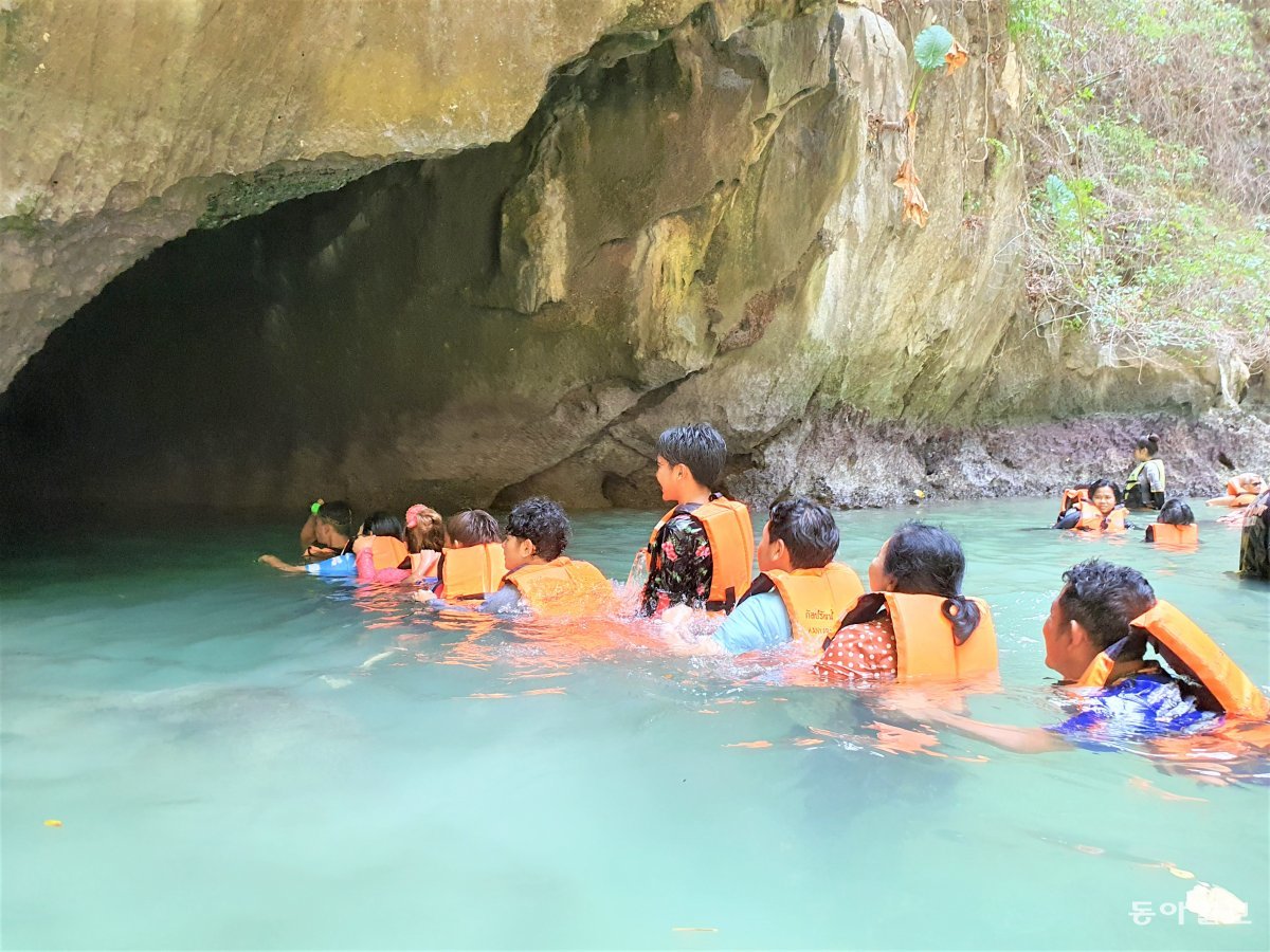 에메랄드빛 해변이 펼쳐진 바다동굴 내부에서 다시 바다로 나가기 위해 관광객들이 한 줄로 늘어서 있다.