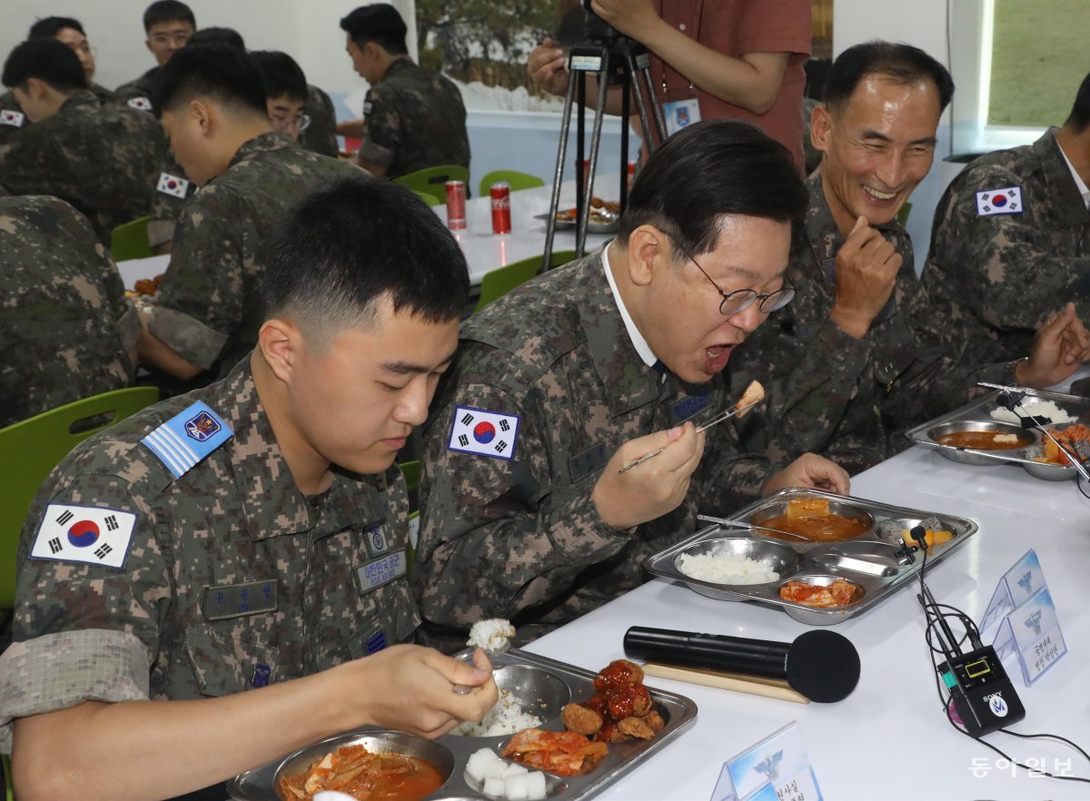 이재명 더불어민주당 대표(가운데)가 23일 강원 강릉시 공군 제18전투비행단을 방문해 오홍균 단장(오른쪽) 및 장병들과 식사를 하고 있다.  이 대표는 치킨을 담지 않았다. 뉴스1