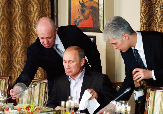 예브게니 프리고진(왼쪽)이 2011년 11월 러시아 모스크바에 있는 자신의 레스토랑에서 블라디미르 푸틴 당시 총리 (가운데)에게 음식을 제공하고 있다. [뉴시스]