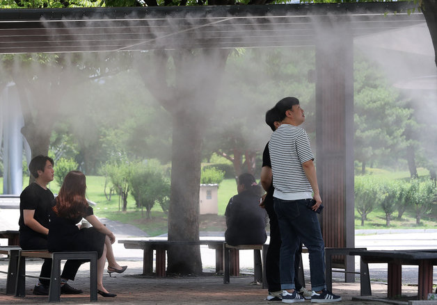 서울의 낮 최고기온이 34도까지 오르는 등 불볕더위가 이어진 3일 오후 서울 영등포구 여의도공원에서 시민들이 무더위를 피해 쿨링포그(안개형 냉각수)가 가동되는 벤치에서 휴식을 취하고 있다. 2023.7.3/뉴스1