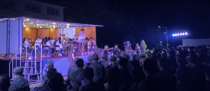 심포니 송의 군부대 공연에서 군인들이 무대 앞으로 나와 춤을 추고 있다.