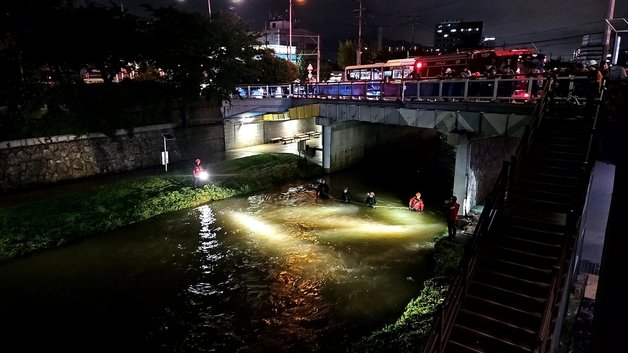 부산에 집중호우가 내린 11일 밤 부산 사상구 학장천에서 소방대원들이 야간 수색 작업을 벌이고 있다. 이날 오후 3시25분께 부산 사상구 학장천에서 60대 여성 A씨가 물에 휩쓸려 실종됐다. 2023.7.11 뉴스1