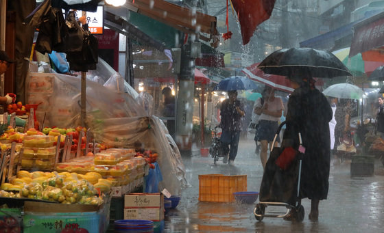 서울 전역에 호우주의보가 발효된 13일 서울 동작구 남성사계시장에 시민들이 우산을 쓴 채 발걸음을 옮기고 있다.남성사계시장은 지난해 8월 폭우로 시장 점포 60여곳이 피해를 입었었다.2023.7.13/뉴스1