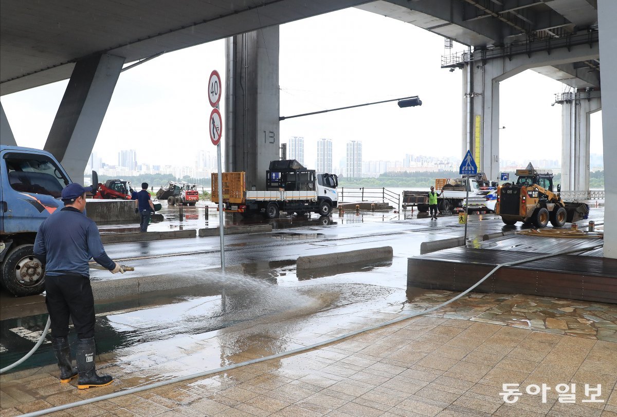 18일 팔당댐 방류량이 줄어들면서 통제됐던 서울 잠수교에서 인부들이 도로 재개를 위해 정비작업을 펼치고 있다. 김재명 기자 base@donga.com