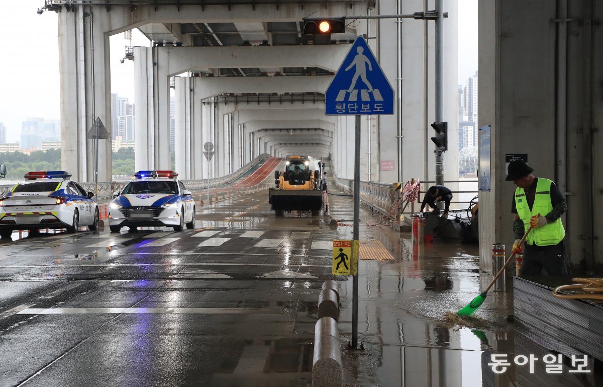 18일 팔당댐 방류량이 줄어들면서 통제됐던 서울 잠수교에서 인부들이 도로 재개를 위해 정비작업을 펼치고 있다. 김재명 기자 base@donga.com
