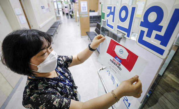 코로나19 위기 경보 수준이 ‘심각’에서 ‘경계’로 하향 된 1일 서울 광진구 인구보건복지협회 가족보건의원에서 직원이 마스크 착용 안내문을 떼고 있다.2023.6.1/뉴스1 ⓒ News1