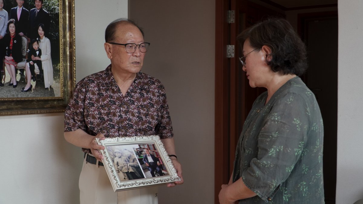 22일 1세대 이산가족인 윤일영 씨(왼쪽)가 ‘그리운 얼굴 프로젝트’에 참여한 김서경 작가(오른쪽)에게 어린 시절 고향에서 찍은 가족사진을 보여주고 있다. 우리의 소원 제공
