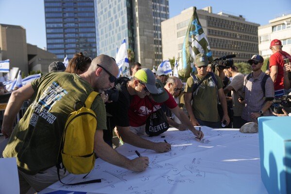 지난달 19일 이스라엘 예루살렘에서 열린 사법 조정안 반대 시위에서 이스라엘 예비군들이 복무 거부 선언에 동참하는 서명을 하고 있다. 예루살렘=AP 뉴시스