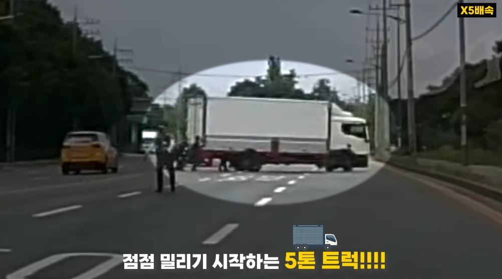 지난달 30일 오후 3시경 대전 대덕구의 한 6차선 도로에서 유턴하던 5t 트럭이 기어 고장으로 멈춰 서자 시민과 경찰관 10여 명이 힘을 합쳐 트럭을 밀고 있다. 대전경찰청 유튜브 캡처