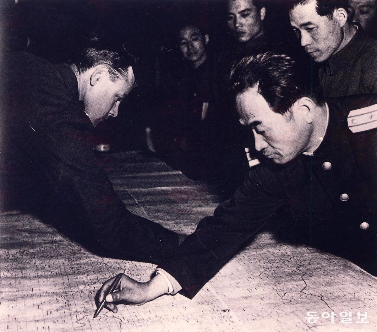 1951년 11월 판문점으로 장소를 옮겨 진행된 휴전회담에서 유엔군과 북한군 장교가 새 휴전선 설정을 논의하기 전 지도에 기존 38선을 긋고 있는 모습. 동아일보DB