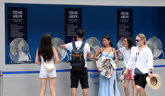 서울 광화문광장에 설치된 건조시설에서 외국인 관광객들이 땀에 젖은 옷을 말리고 있다. 2023.7.26/뉴스1