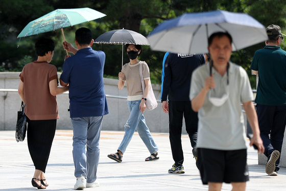 장마전선이 물러간 뒤 서울 지역 낮 최고기온이 33도를 넘어 폭염주의보가 발령된 19일 오후 서울 용산구 국립중앙박물관을 찾은 시민들이 양산을 펼쳐 따가운 햇빛을 피하고 있다. 2023.7.19/뉴스1