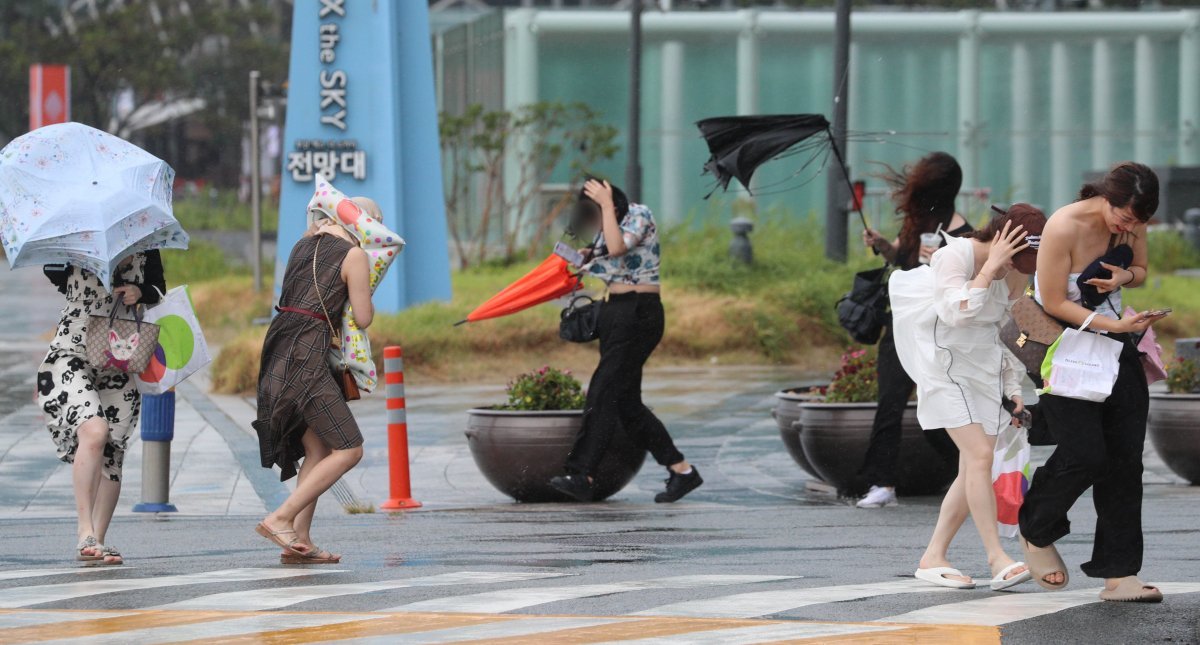 6호 태풍 '카눈'의 영향권에 접어든 9일 오후 부산 해운대구 해운대해수욕장 엘시티 앞에서 중국인 관광객 이 강풍을 동반한 비에 맞서 힘겹게 걸어가고 있다. 뉴시스