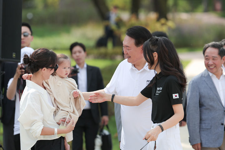 윤석열 대통령과 부인 김건희 여사가 26일 서울 용산어린이정원 내 분수정원에서 열린 다둥이가족 초청 행사에 깜짝 방문해 어린이와 인사하고 있다. 대통령실 제공