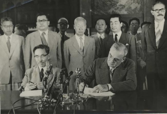 1953년 8월 8일 경무대에서 열린 한미상호방위조약 가조인식. 변영태 외무 장관과 존 포스터 덜레스 미 국무 장관(앞에 앉은 이들)이 서명하는 모습을 이승만 대통령(가운데)이 지켜보고 있다.  이승만대통령기념사업회