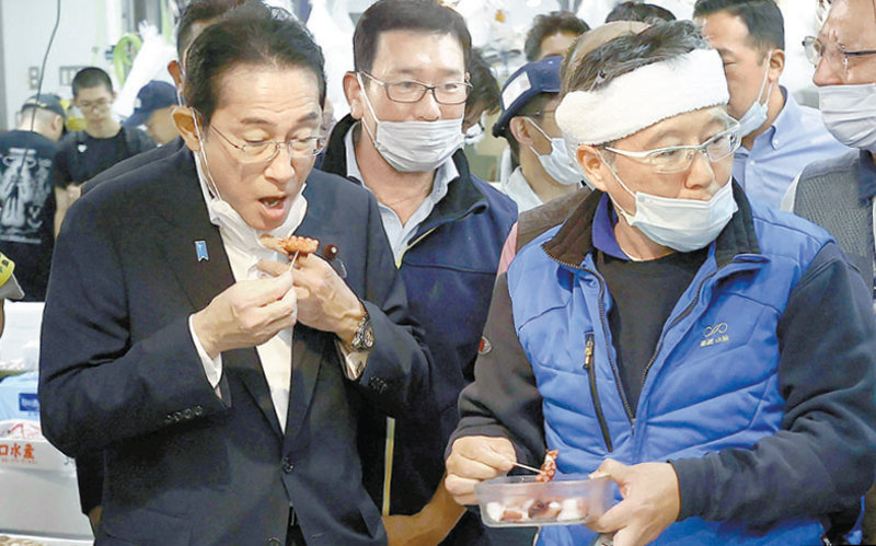 지난달 31일 기시다 후미오 일본 총리(왼쪽)가 도쿄 도요스 수산시장에서 해산물을 시식하고 있다. 도쿄=AP 뉴시스