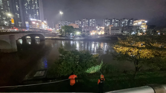 부산지역에 호우특보가 내려진 지난 20일 오후 부산 금정구 온천천 산책로에서 한 여성이 폭우로 불어난 물에 휩쓸려 실종된 가운데 소방대원들이 수색작업을 벌이고 있다. (부산소방재난본부 제공)