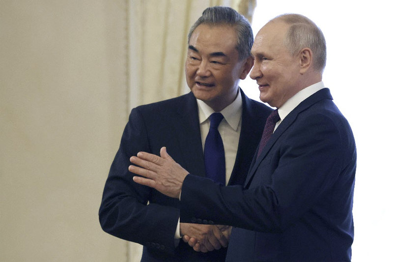 블라디미르 푸틴 러시아 대통령(오른쪽)이 20일 자신의 고향인 2대 도시 상트페테르부르크에서 왕이 중국 외교부장과 만나 악수하며 기념 촬영을 하고 있다. 상트페테르부르크=AP 뉴시스