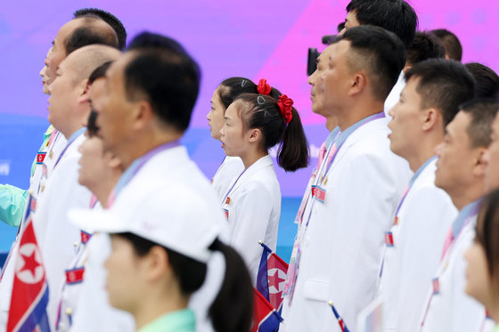 2022 항저우 아시안게임 개막을 하루 앞둔 22일 오전 중국 항저우 아시안게임 선수촌 국기광장에서 열린 입촌식에서 북한 선수단이 인공기가 게양되는 모습을 지켜보며 국가를 제창하고 있다. 2023.9.22 뉴스1
