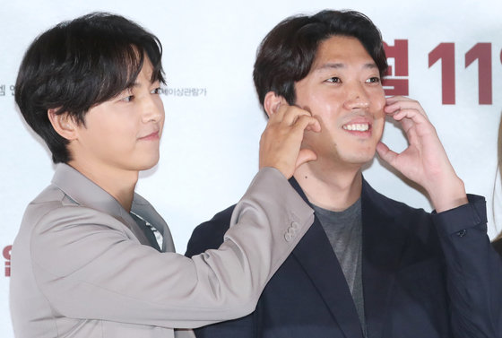 배우 송중기(왼쪽)가 22일 서울 강남구 메가박스 코엑스에서 열린 영화 ‘화란‘ 언론시사회에서 김창훈 감독의 볼에 하트를 그리고 있다.