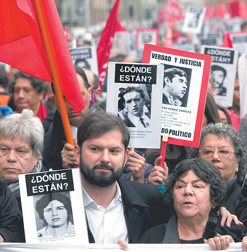 가브리엘 보리치 칠레 대통령(왼쪽에서 두 번째)이 10일 수도 산티아고에서 군인 출신 우익 독재자 아우구스토 피노체트 전 대통령 치하에서 희생된 사람들의 얼굴이 그려진 팻말을 들고 행진하고 있다. 산티아고=AP 뉴시스