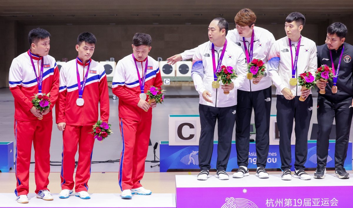 “같이 올라와 사진 촬영” 北 선수들에게 권했지만… 25일 항저우 아시안게임 사격 남자 10m 러닝타깃 정상 단체전에서 금메달을 딴 한국 선수들(왼쪽에서 네 번째부터 하광철, 
정유진, 곽용빈)이 은메달을 차지한 북한 선수들에게 금메달 단상에 함께 설 것을 권하고 있다. 하지만 북한 선수들은 끝내 은메달 
단상에서 기념 사진을 찍었다. 북한 선수들은 한국 선수들이 청한 악수에도 응하지 않았다. 금메달 단상의 맨 오른쪽은 동메달을 딴 
인도네시아 선수다. 항저우=뉴스1