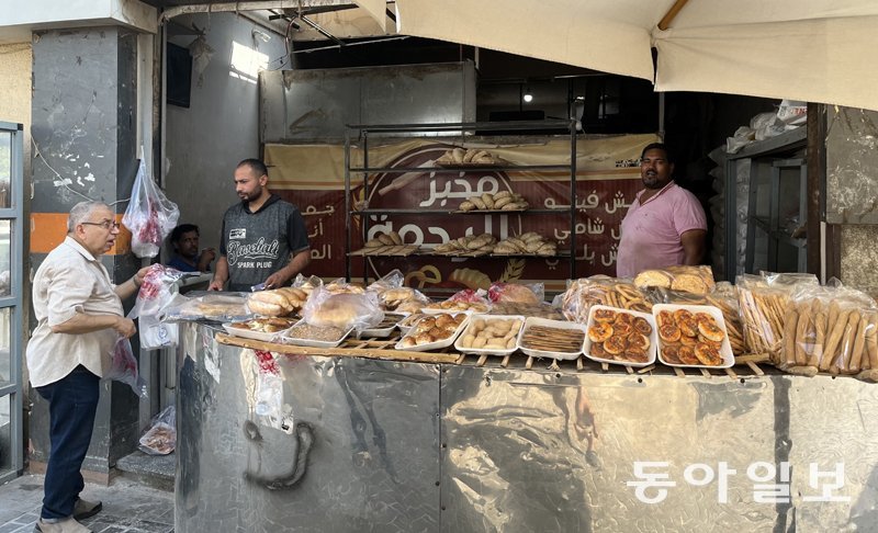 23일(현지 시간) 이집트 카이로 근교 재래시장에서 20년 넘게 빵을 팔고 있는 가게에서 손님(왼쪽)이 빵 가격을 붇고 있다. 서민 주식인 납작한 모양의 빵 ‘아이시 발라디’ 가격은 올 들어 2~5배 급등했다. 카이로=김기윤 특파원 pep@donga.com