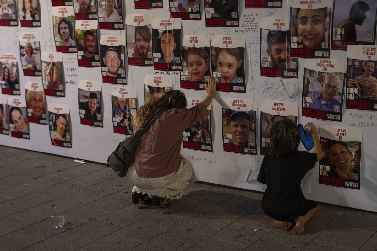 이스라엘 경제 중심지인 텔아비브에서 한 여성과 어린이가 거리 벽에 붙은  하마스에 억류됐거나 가자지구에서 실종된 이스라엘인들의 사진을 만지고 있다.  텔아비브=AP 뉴시스