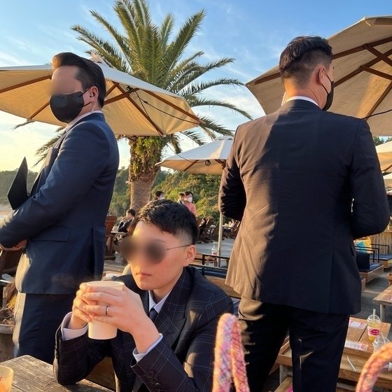 전청조(가운데)씨가 제주도 모 카페에서 경호를 받고 있는 모습(김민석 강서구 의원 제공) ⓒ 뉴스1