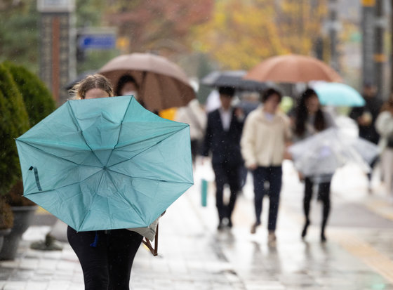 서울 지역에 강풍주의보가 발령된 6일 오후 서울 세종대로의 거리에서 한 시민이 바람에 뒤집힌 우산을 정돈하고 있다. 2023.11.6/뉴스1