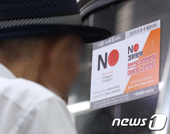 2019년 8월 전동차 출입문에 붙은 서울교통공사노조의 ‘반일 선전물’을 한 노인 승객이 들여다고보 있다.