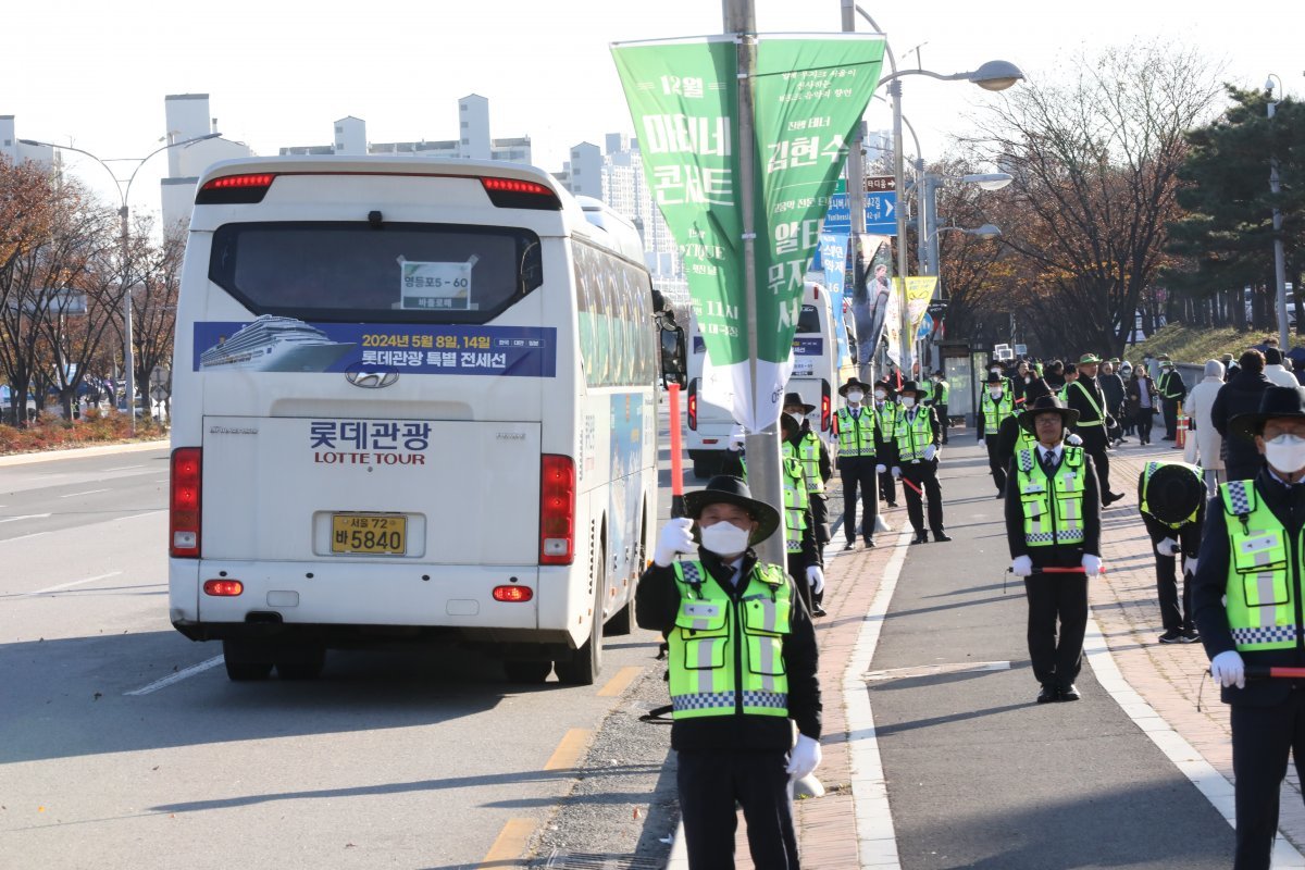 교통 안내 봉사자가 수료생이 탄 버스를 안내하고 있다.