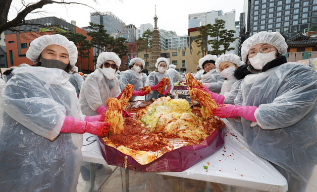 29일 오전 서울 종로구 조계사 대웅전 앞마당에서 열린 이웃과 함께 따뜻한 조계사 김장 나눔전에서 신도들이 김치를 들어보이고 있다. 2023.11.29/뉴스1