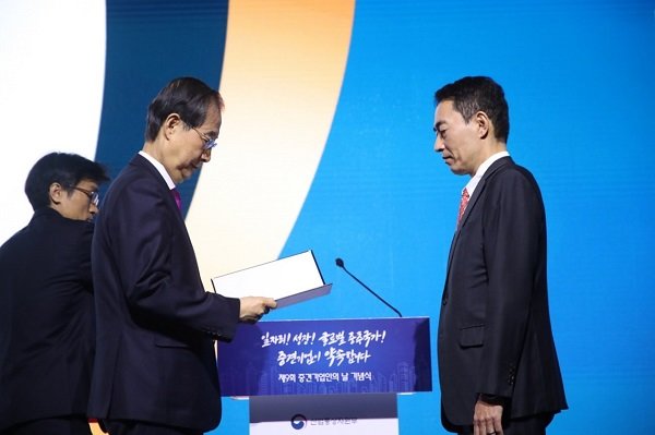 TYM 김도훈 대표(오른쪽)가 한덕수 국무총리로부터 대통령 표창을 수여받고 있다. 사진제공=TYM
