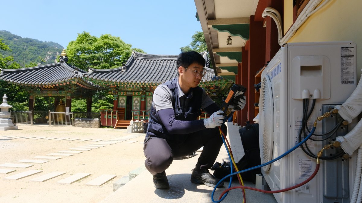 삼성전자서비스 엔지니어가 가전제품 점검 장비와 부품을 갖고 북한산 중턱의 사찰에 올라 에어컨을 점검하는 모습.