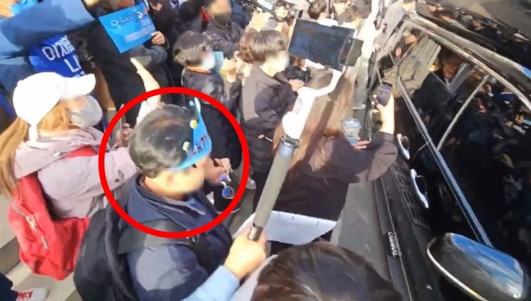 지난달 13일 부산에서 더불어민주당 부산지역 전세사기 피해자 간담회가 열린 당시 이재명 대표의 차량 앞에 서 있는 파란색 종이 왕관을 쓴 남성(빨간 원). X(옛 트위터) 캡처
