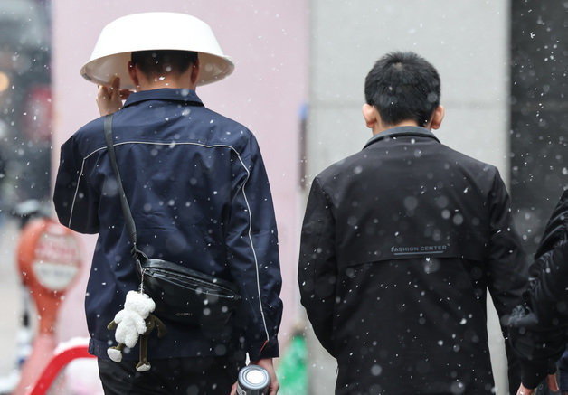 전국에 많은 눈이 내리는 9일 오후 서울 중구 명동 거리에서 한 시민이 바가지를 머리에 쓰고 걷고 있다. 2024.1.9 뉴스1
