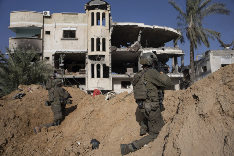 이스라엘 군인들이 10일 가자지구 남부 중심 도시인 칸유니스에서 파괴된 건물 앞에 진을 치고 총을 겨누고 있다. 가자지구=AP 뉴시스