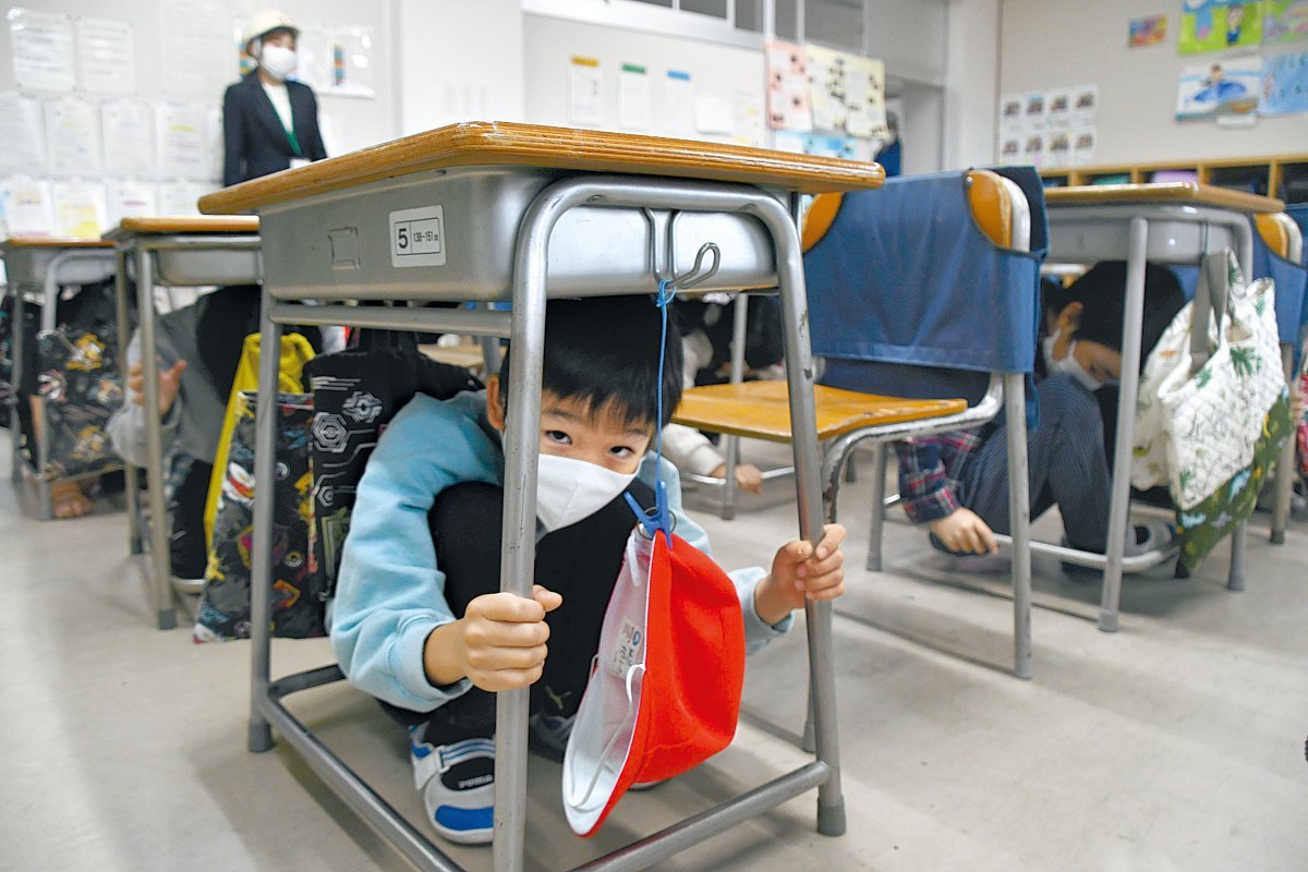 지난해 11월 일본 센다이시의 한 초등학교에서 학생들이 지진 발생 시 책상 밑으로 들어가 몸을 보호하는 훈련을 하고 있다. 아사히신문 제공