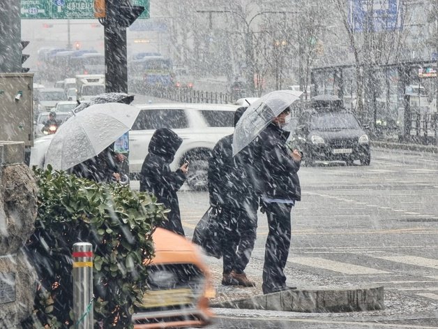전국 대부분 지역에 눈이 내릴 것으로 예보된 17일 오후 서울 서대문구 서대문역 인근에서 시민들이 함박눈을 맞으며 이동하고 있다. 2024.1.17. 뉴스1