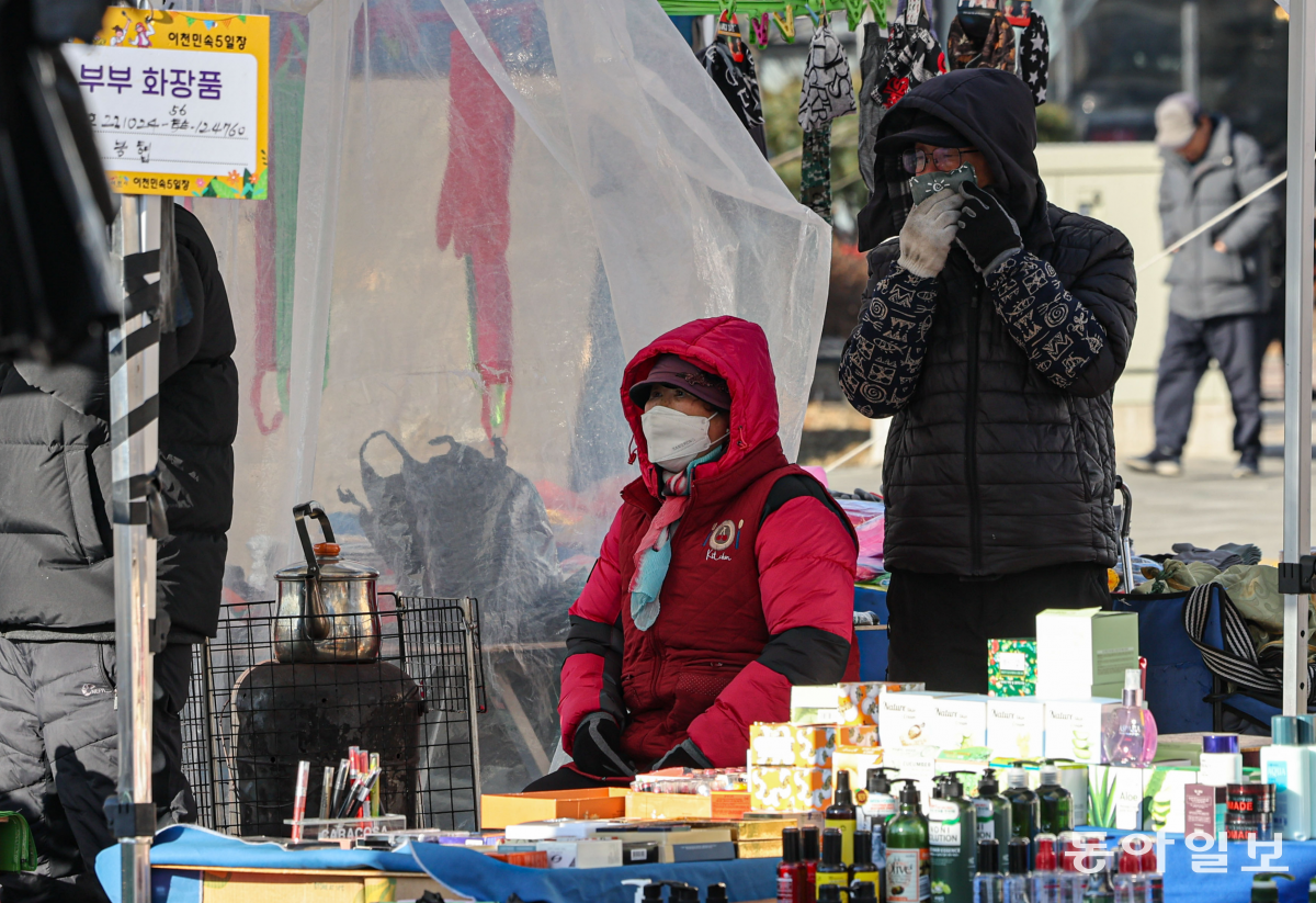 24일 경기도 성남시 모란민속5일장에서 상인들이 난로와 핫팩으로 몸을 녹이고 있다. 성남=이한결 기자 always@donga.com