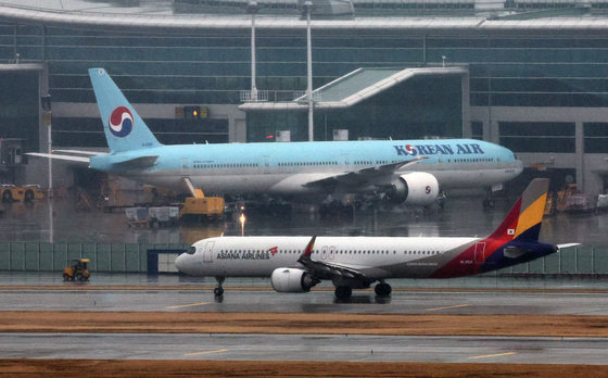 14일 오후 인천국제공항 계류장에 세워진 대한항공 항공기 앞으로 아시아나 항공기가 지나가고 있다. 2024.1.14 뉴스1