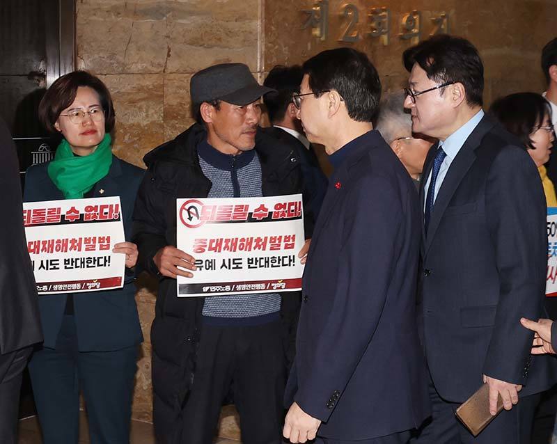 정의당과 한국노총 및 민주노총 회원들이 ‘중대재해처벌법 개악 협상 중단 촉구’ 피켓팅을 하는 가운데 홍익표 더불어민주당 원내대표가 1일 서울 여의도 국회에서 비공개로 열린 더불어민주당 의원총회 회의장에 들어가고 있다. 2024.2.1. 뉴스1