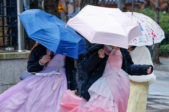 서울 지역에 눈이 내리는 21일 종로구 경복궁 인근에서 한복을 입은 시민들이 발걸음을 재촉하고 있다. 2024.2.21/뉴스1