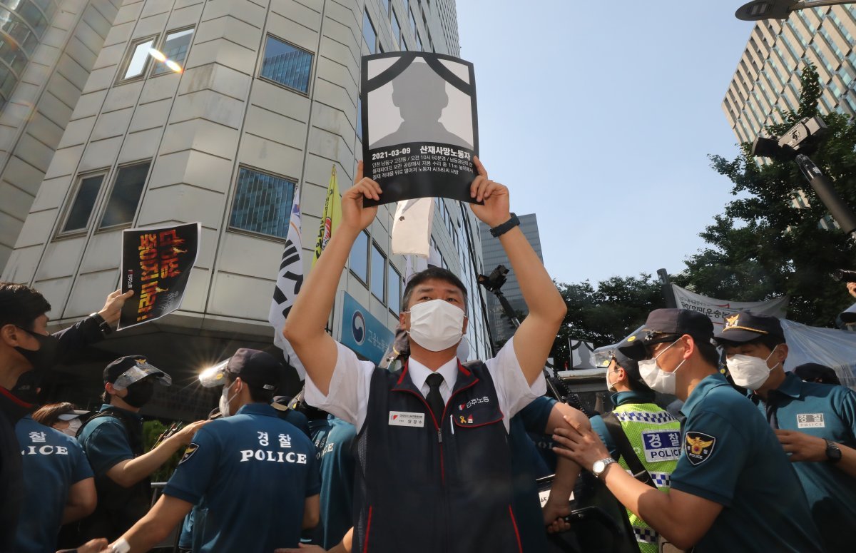 19일 서울 중구 서울고용노동청 앞에서 민주노총 주최로 열린 ‘더 이상 죽이지 마라!’ 중대재해 노동자 합동추모제 집회에서 양경수 민주노총 위원장이 산재로 숨진 노동자 영정을 들고 시위를 하고 있다. 2021.6.19. 뉴스1