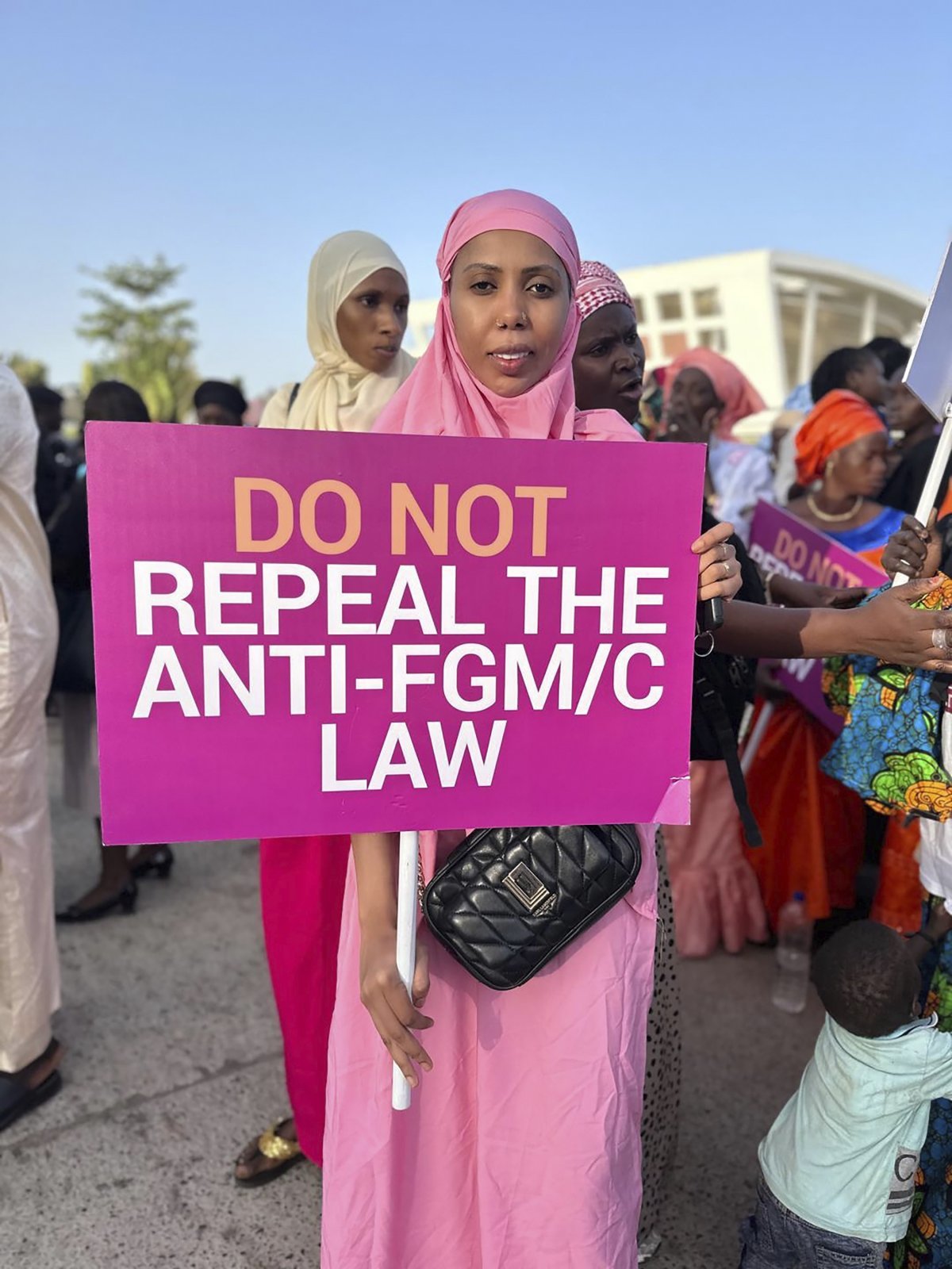 시민단체 ‘세이프 핸즈 포 걸스’ 설립자 자하 두쿠레가 18일(현지시각) 감비아 세레쿤다 의회 밖에서 FGM(여성성기훼손) 금지법 폐기에 반대하는 피켓을 들고 시위하고 있다. 어린 시절 할례 시술을 당한 후 시민단체를 설립한 두쿠레는 지난 2015년 통과한 여성 할례 금지법을 감비아 의회가 폐지하려는 움직임을 보이자 이에 항의하고 나섰다. 2024.03.19. [세레쿤다=AP/뉴시스]