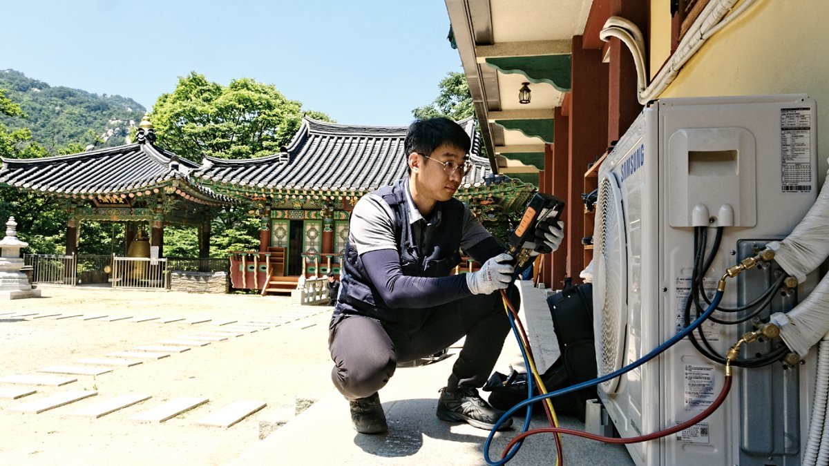 삼성전자서비스 엔지니어가 장비와 부품을 갖고 북한산 중턱의 사찰에 올라 에어컨을 점검하는 모습.