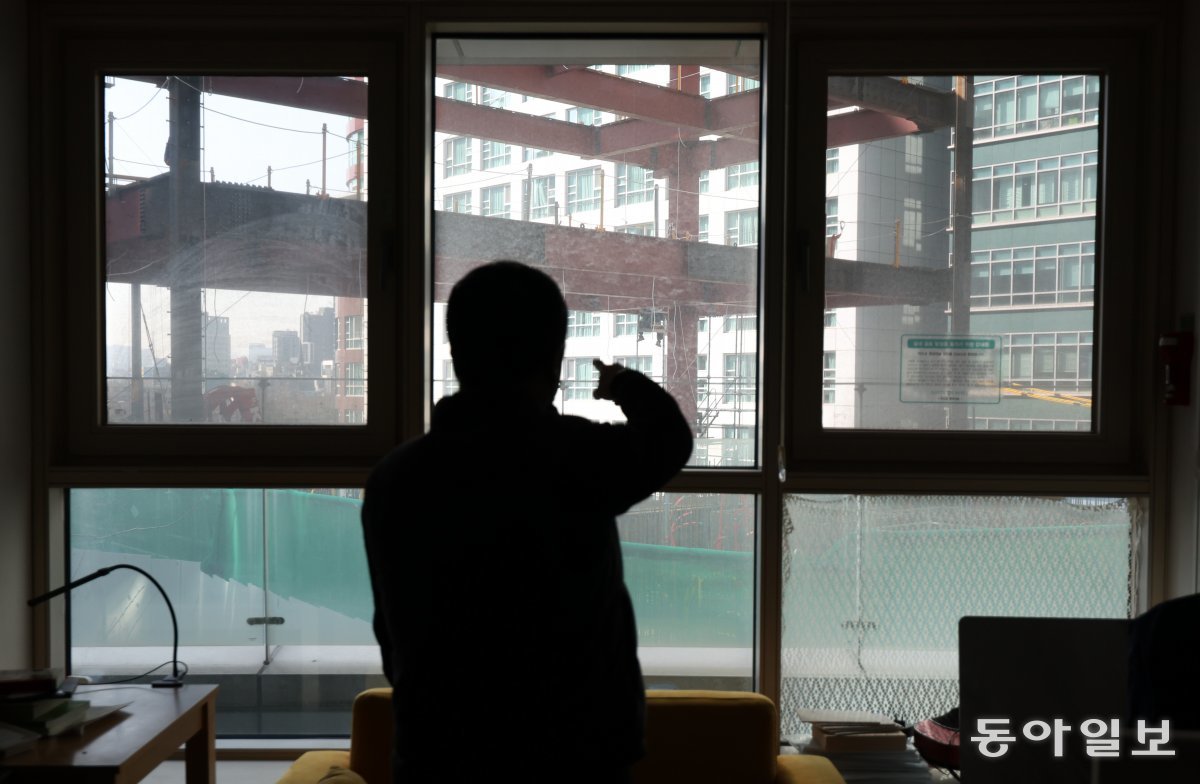 서울 중구의 한 오피스텔 입주자가 자신의 집 창문 앞에서 B 기업의 본사 건설 현장을 가리키고 있다. 철골 아래로 나와 있는 것은 현장 작업자의 하반신 모습. 최혁중 기자 sajinman@donga.com