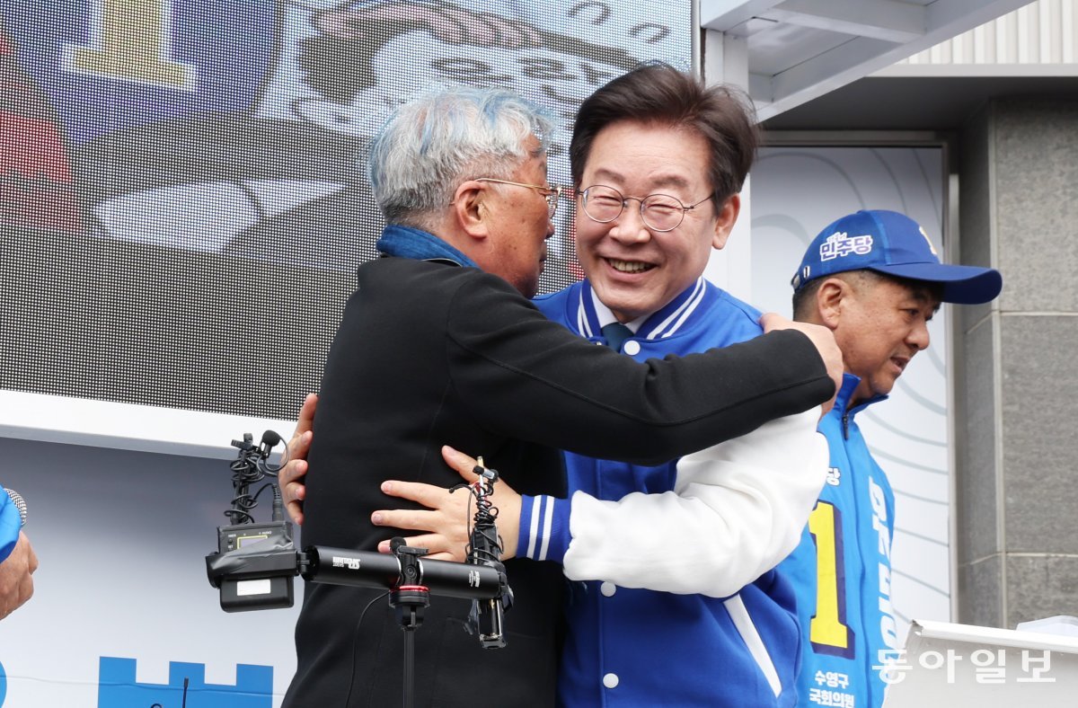 이재명 더불어민주당 대표가 4일 오후 부산 수영구 광안동 일대에서 유동철 수영구 후보 지지 발언을 하기 전 배우 명계남 씨와 포옹하고 있다. 부산=최혁중 기자 sajinman@donga.com