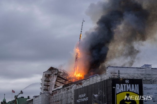 16일(현지시각) 덴마크 코펜하겐의 ‘뵈르센’(옛 증권거래소) 건물에 불이 나 17세기에 세워진 56m 높이의 첨탑이 무너지고 있다.   [AP/뉴시스]